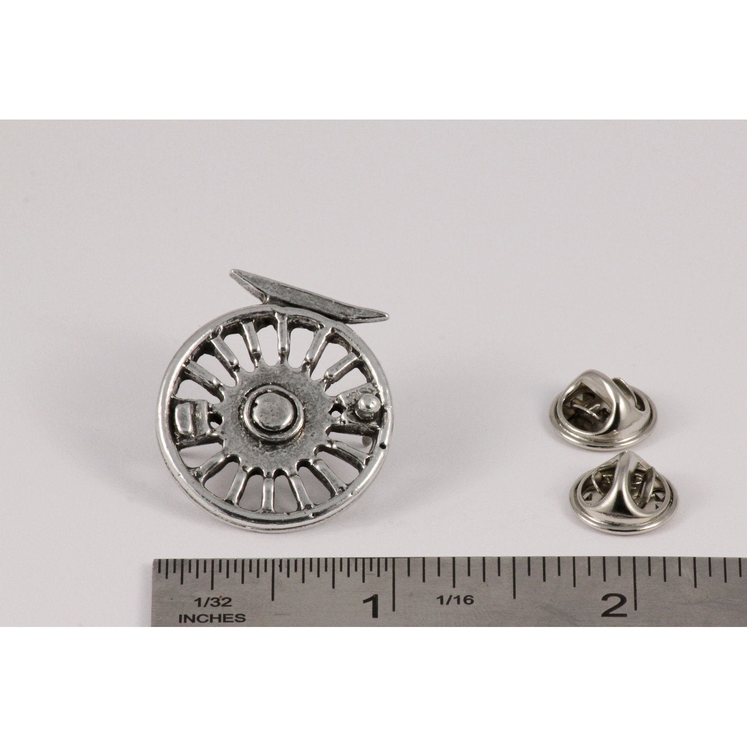 A handcrafted Fly Reel Pin next to a ruler, available for sale at Creativeartisan.com - the image offers a sense of scale
