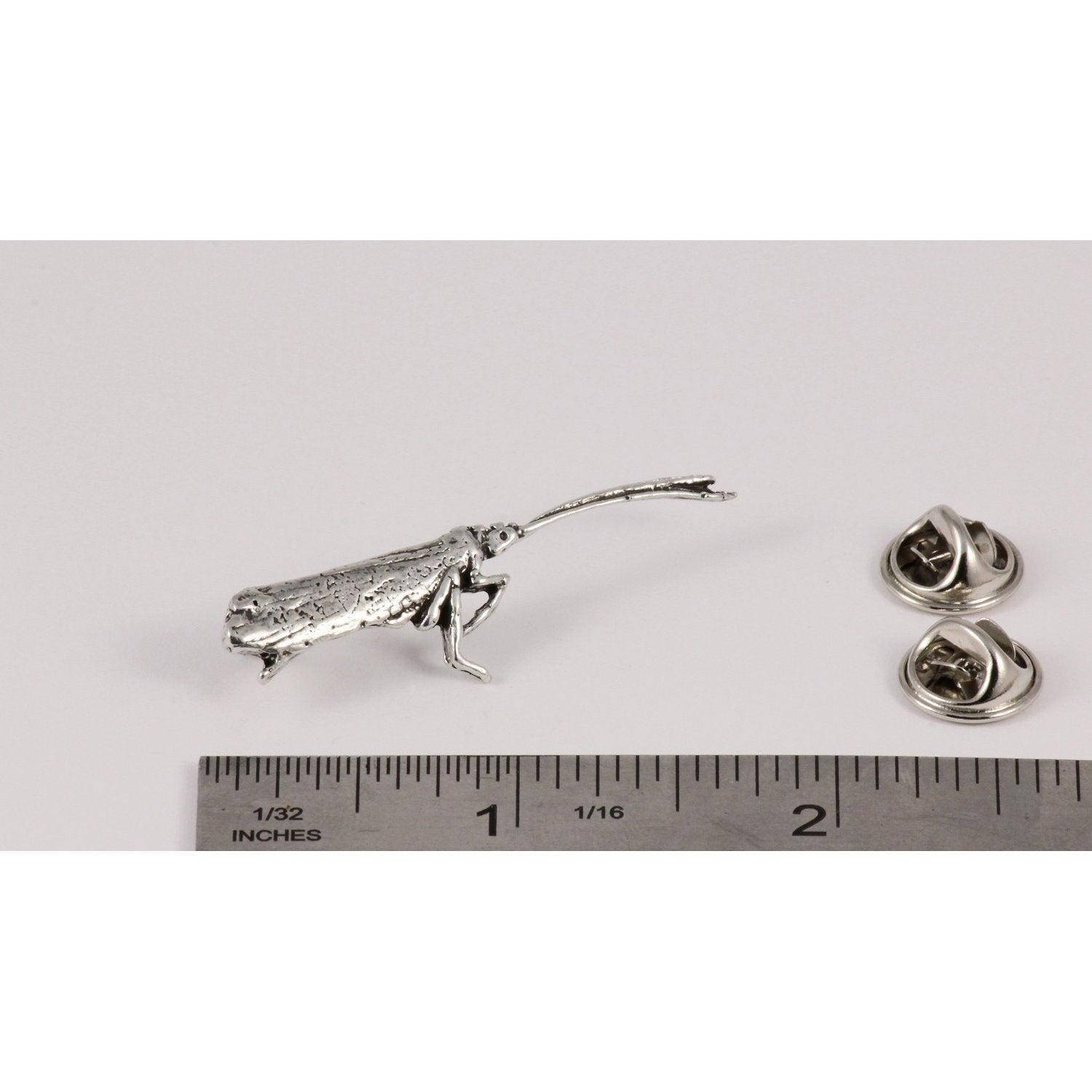 A handcrafted Caddis Pin next to a ruler, available for sale at Creativeartisan.com - the image offers a sense of scale