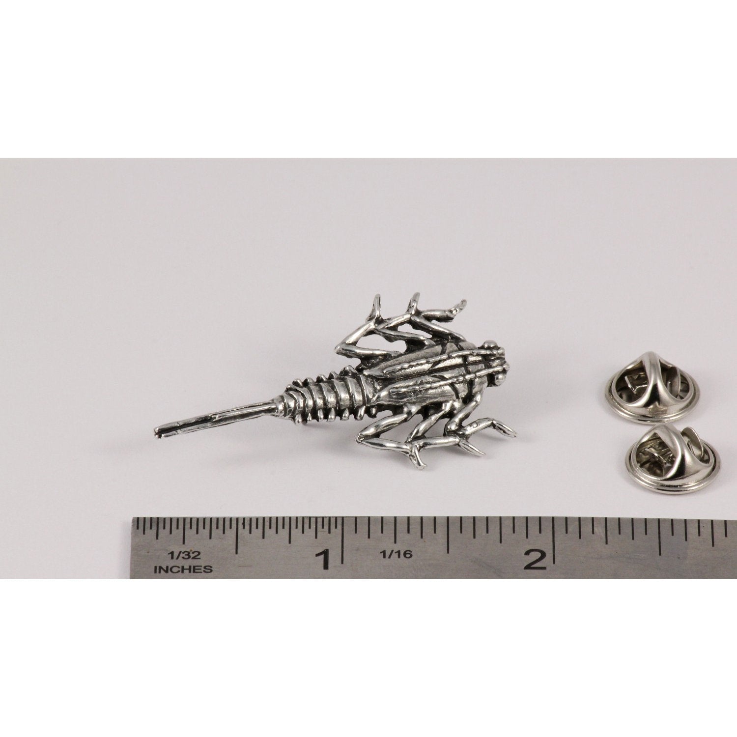 A handcrafted Stone Fly Pin next to a ruler, available for sale at Creativeartisan.com - the image offers a sense of scale