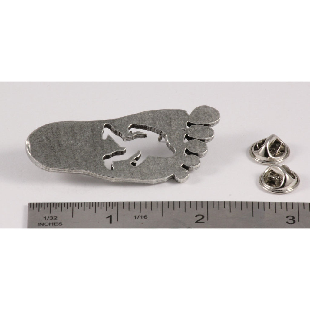 A handcrafted Sasquatch Bigfoot Footprint Pin next to a ruler, available for sale at Creativeartisan.com - the image offers a sense of scale