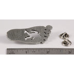 A handcrafted Sasquatch Bigfoot Footprint Pin next to a ruler, available for sale at Creativeartisan.com - the image offers a sense of scale
