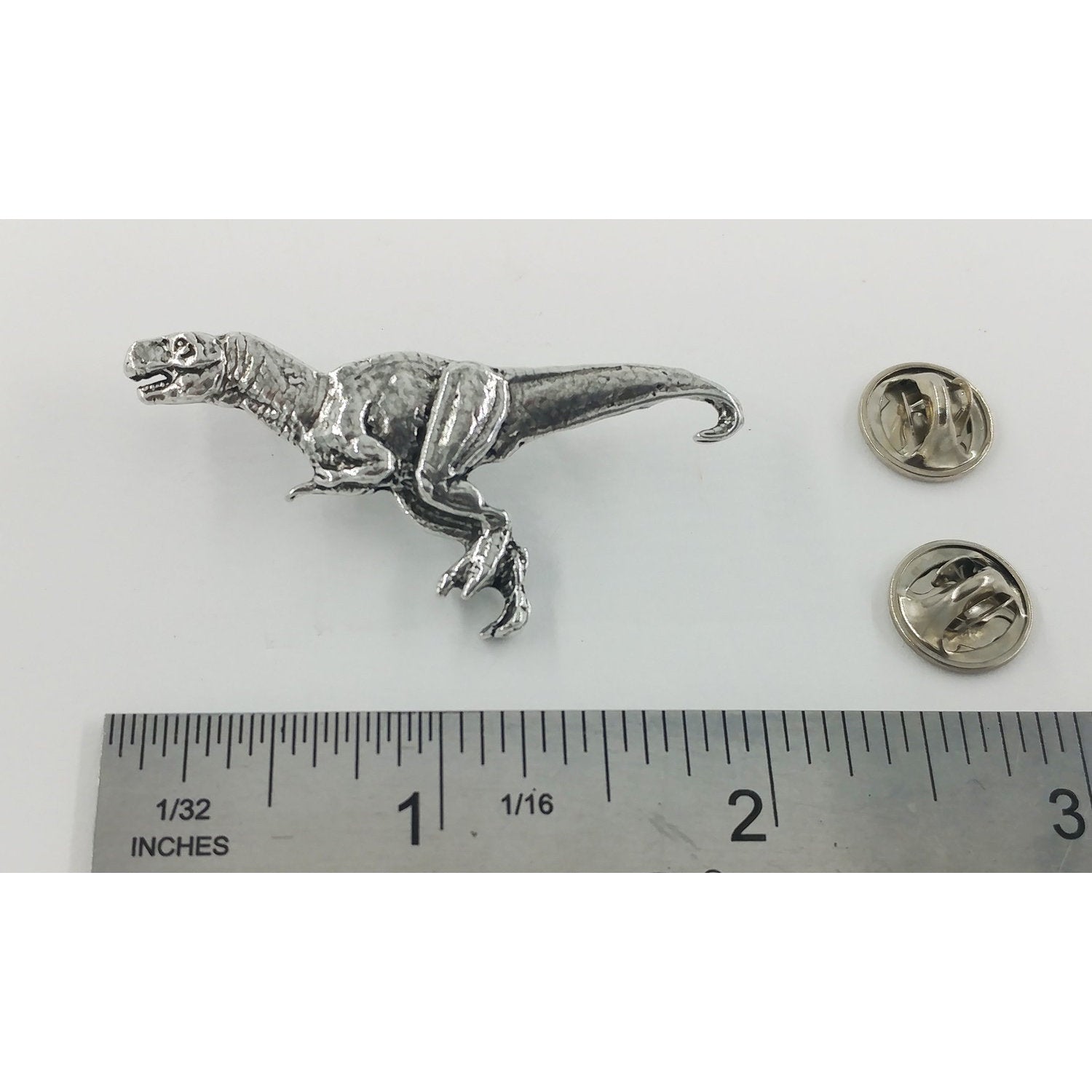A handcrafted Tyrannosaurus Rex Pin next to a ruler, available for sale at Creativeartisan.com - the image offers a sense of scale