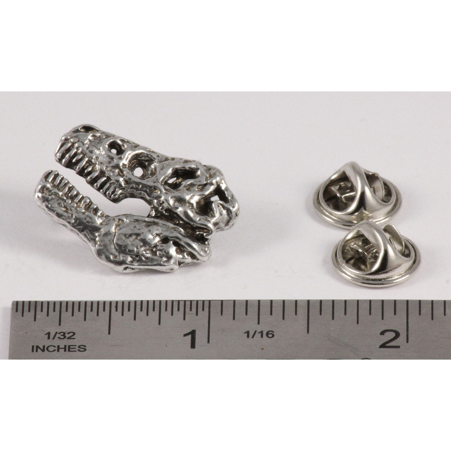 A handcrafted Tyrannosaurus Rex Fossilized Head Pin next to a ruler, available for sale at Creativeartisan.com - the image offers a sense of scale