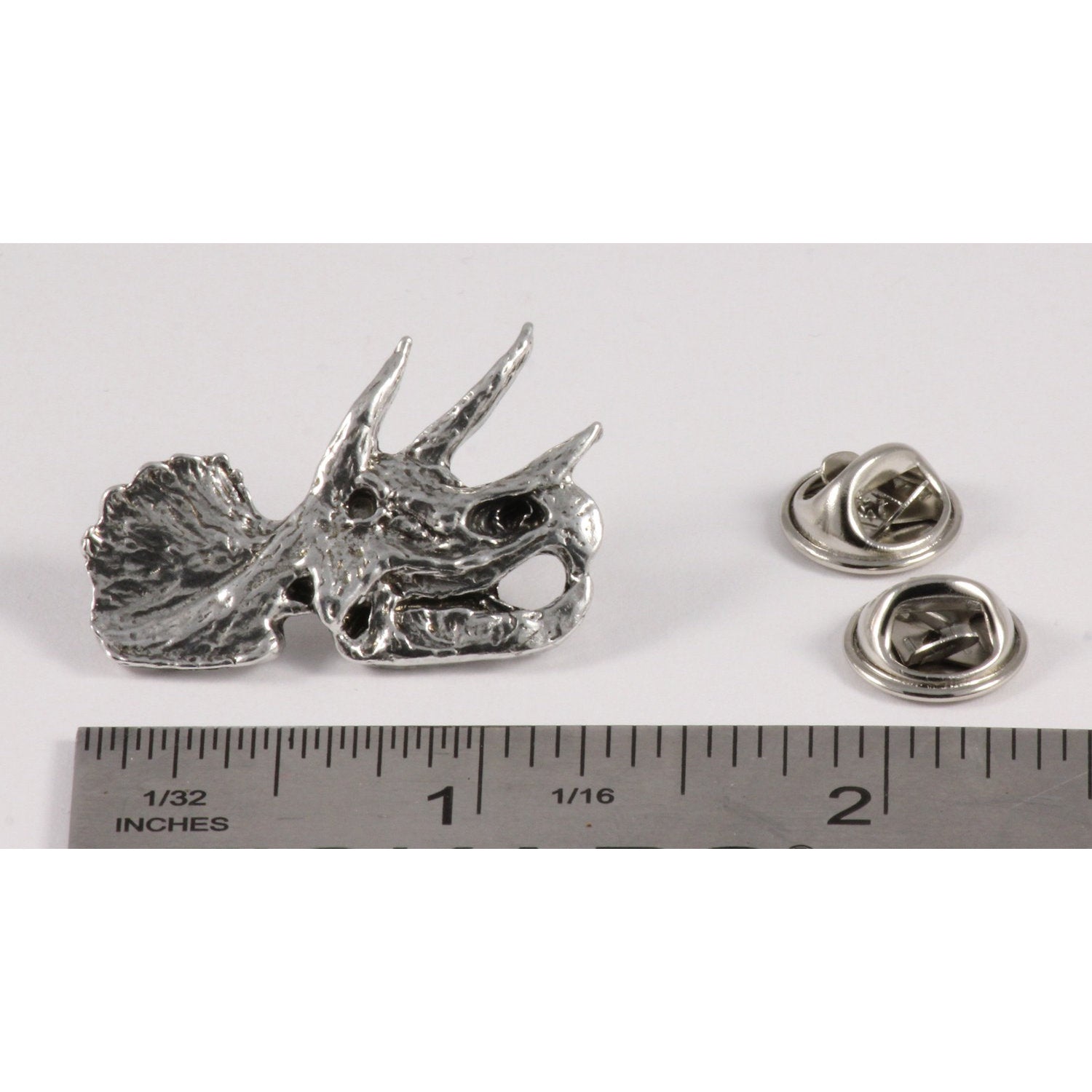 A handcrafted Triceratops Fossilized Head Pin next to a ruler, available for sale at Creativeartisan.com - the image offers a sense of scale