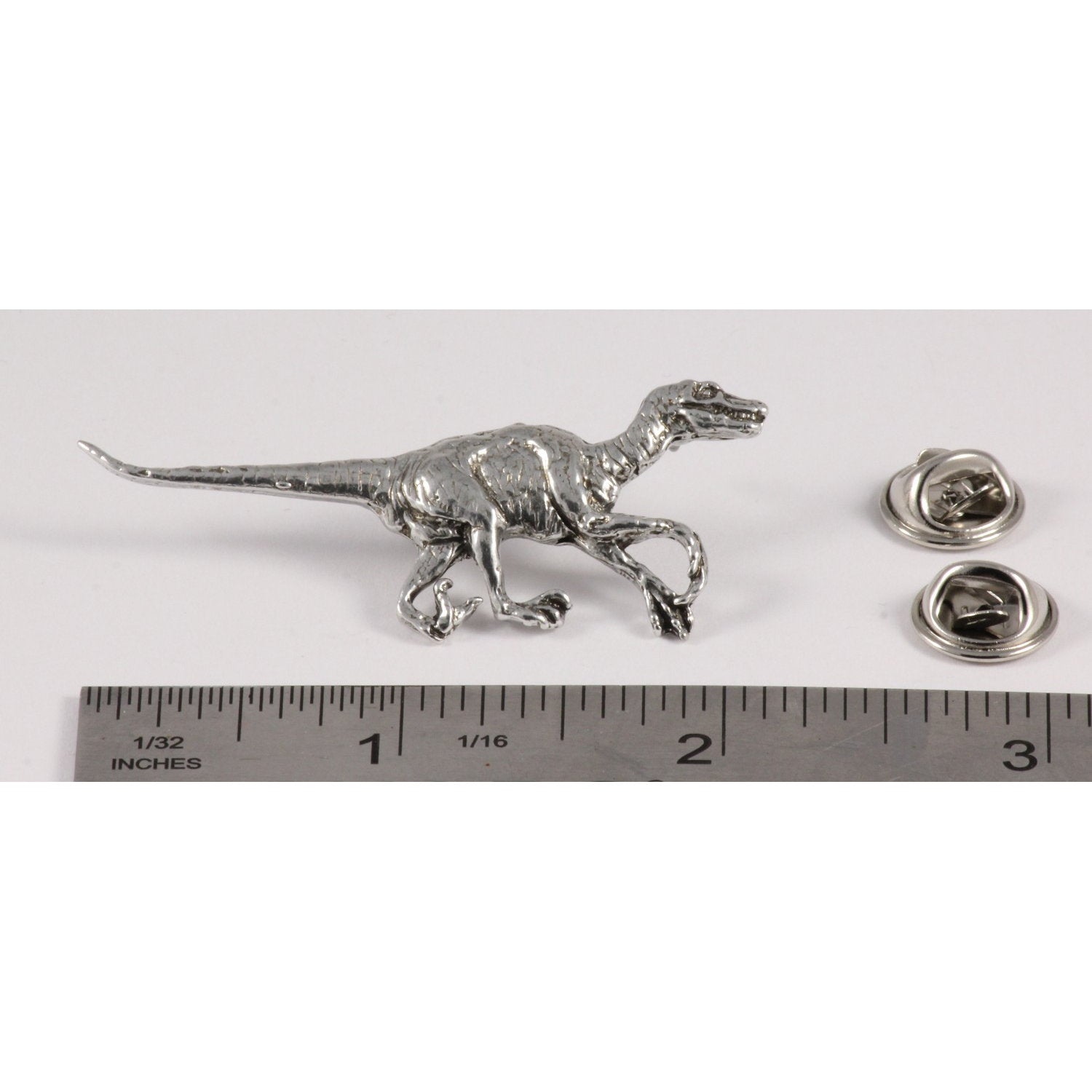 A handcrafted Velociraptor Pin next to a ruler, available for sale at Creativeartisan.com - the image offers a sense of scale