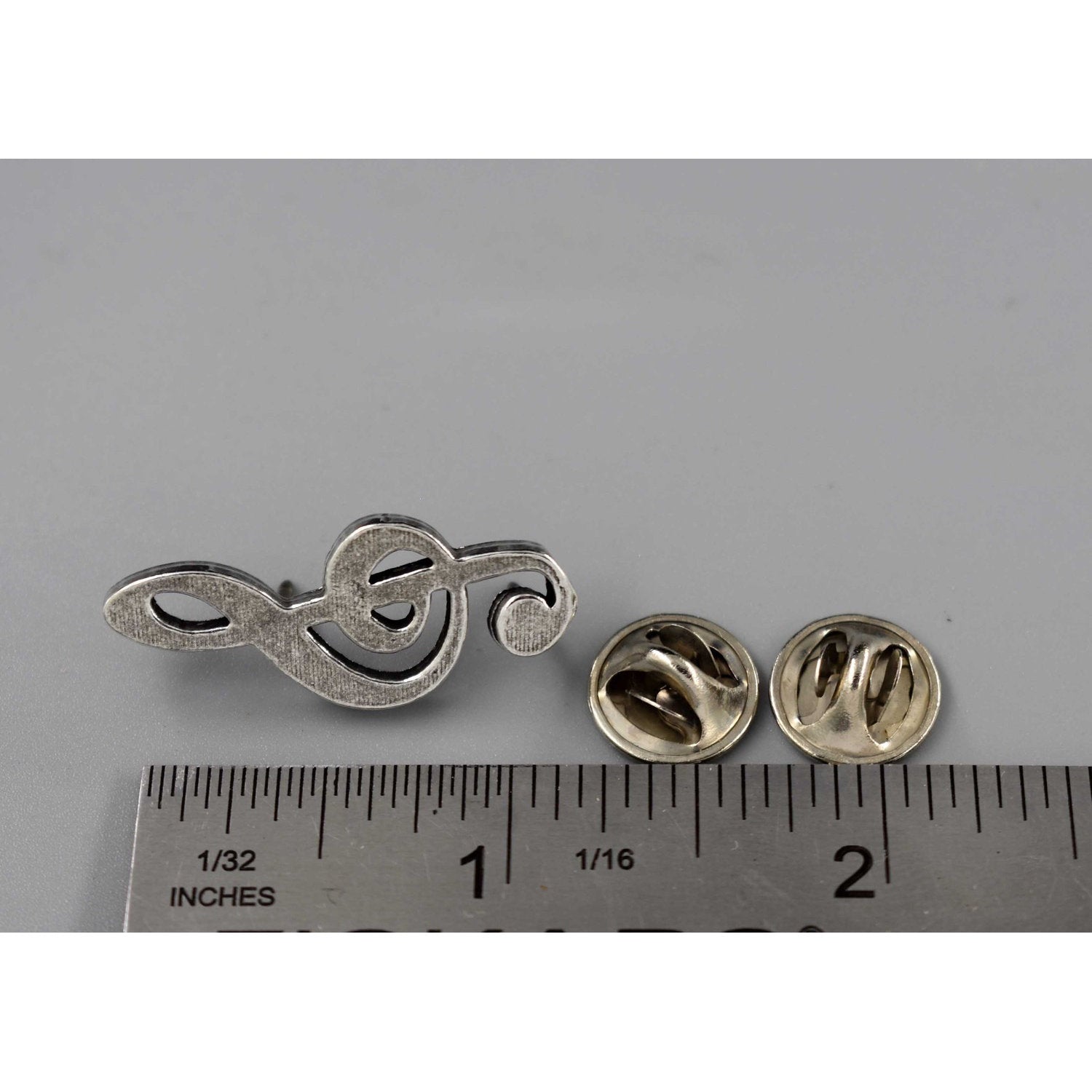 A handcrafted Treble Clef Musical Note Pin next to a ruler, available for sale at Creativeartisan.com - the image offers a sense of scale