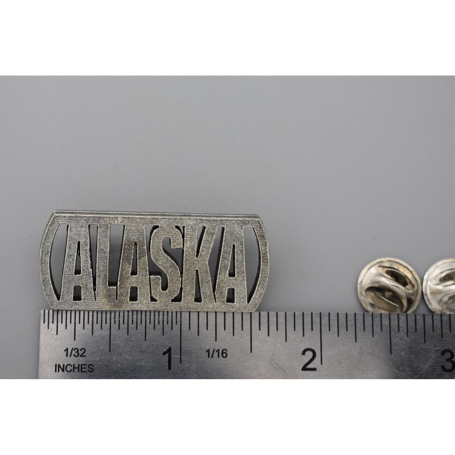 A handcrafted Alaska Cutout Pin next to a ruler, available for sale at Creativeartisan.com - the image offers a sense of scale
