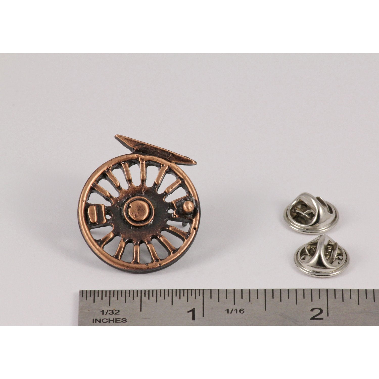 A handcrafted Fly Reel Pin next to a ruler, available for sale at Creativeartisan.com - the image offers a sense of scale