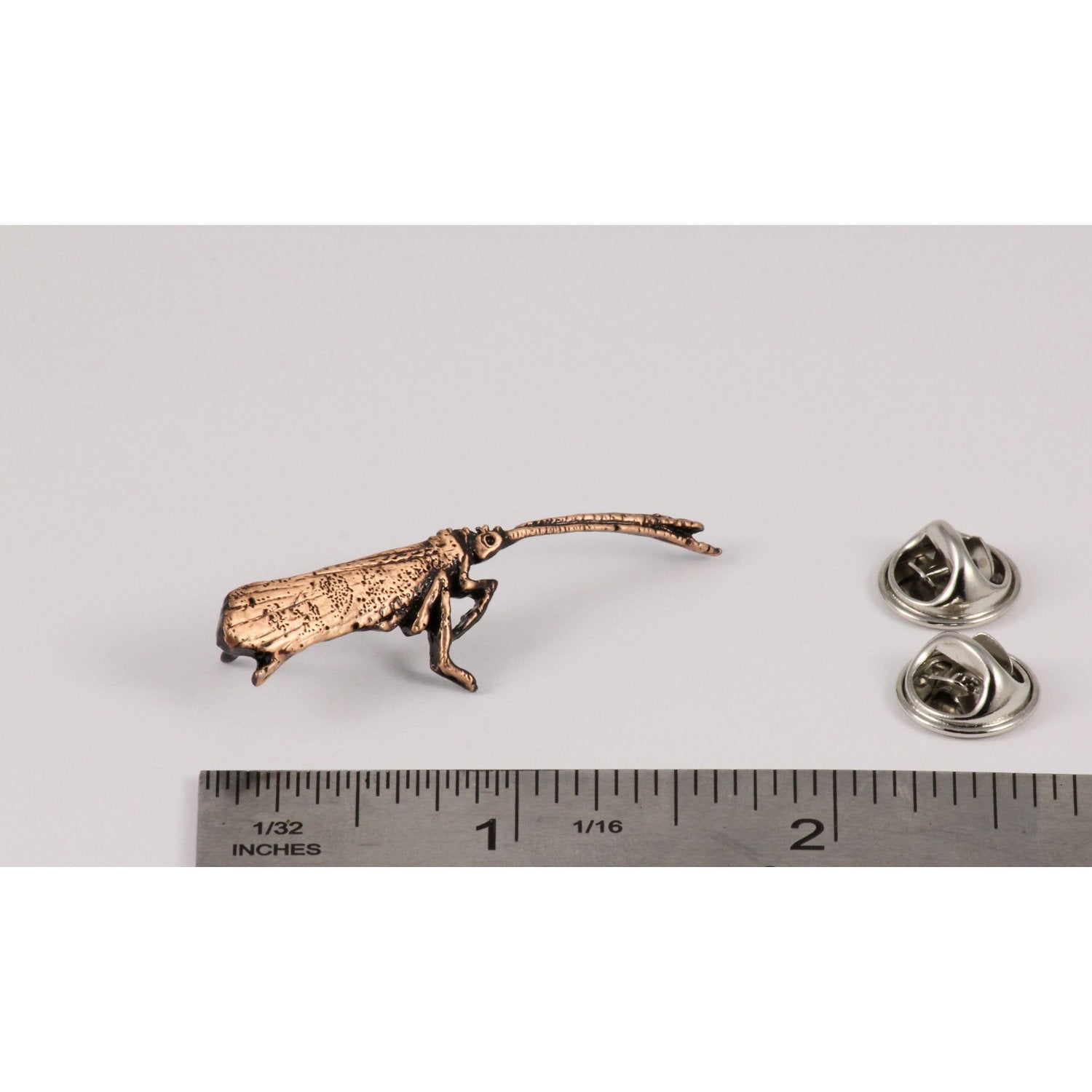 A handcrafted Caddis Pin next to a ruler, available for sale at Creativeartisan.com - the image offers a sense of scale
