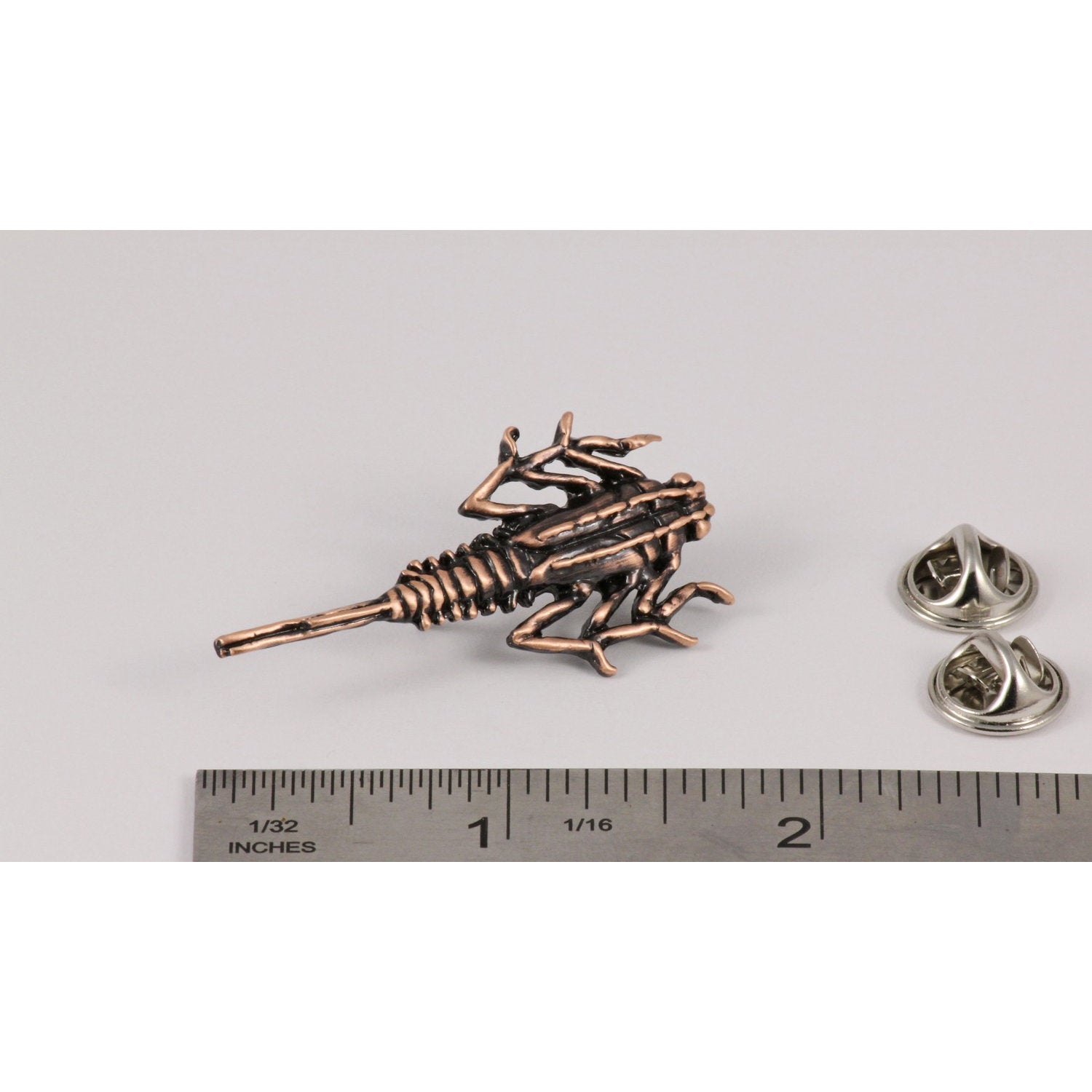 A handcrafted Stone Fly Pin next to a ruler, available for sale at Creativeartisan.com - the image offers a sense of scale