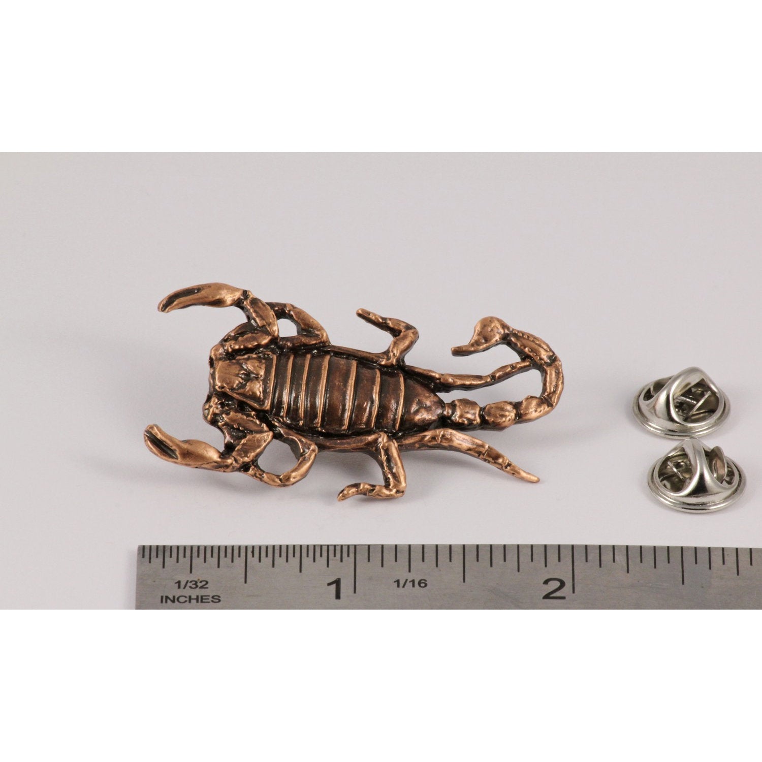 A handcrafted Scorpion Pin next to a ruler, available for sale at Creativeartisan.com - the image offers a sense of scale