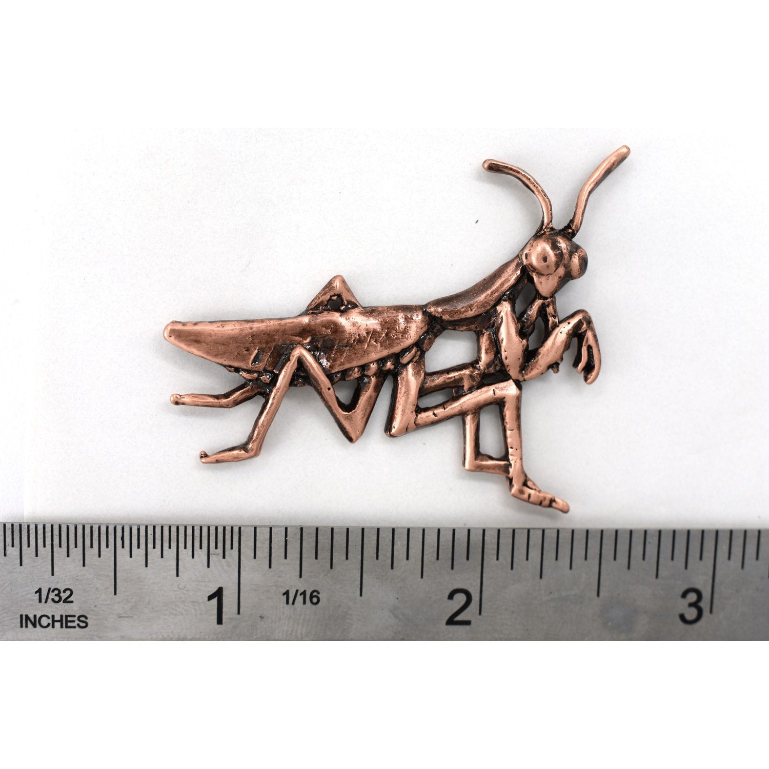 A handcrafted Praying Mantis Pin next to a ruler, available for sale at Creativeartisan.com - the image offers a sense of scale