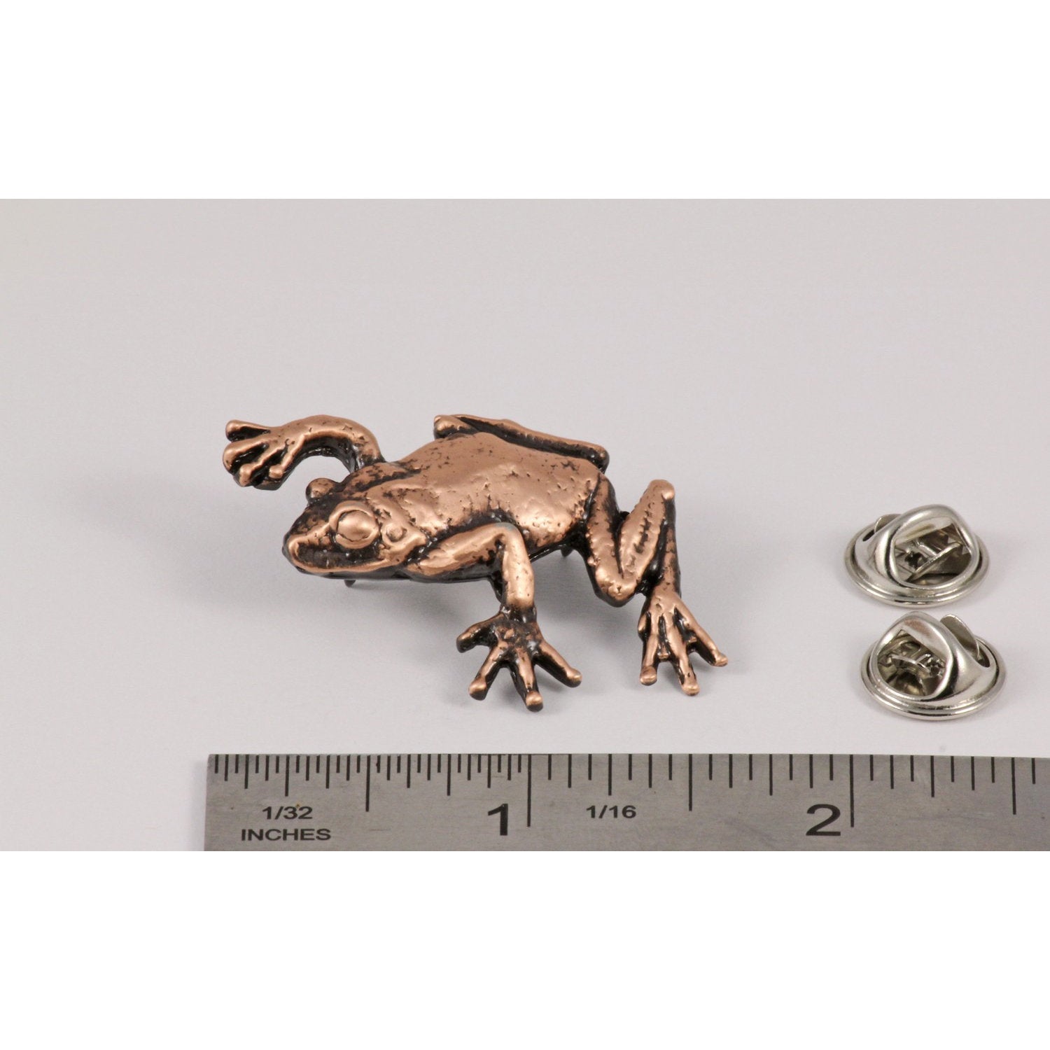 A handcrafted Tree Frog Climbing Pin next to a ruler, available for sale at Creativeartisan.com - the image offers a sense of scale