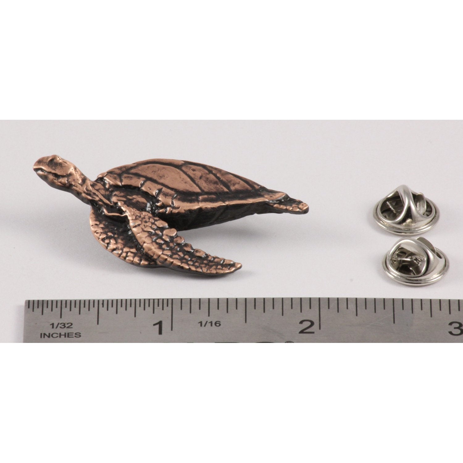 A handcrafted Sea Turtle Side View Pin next to a ruler, available for sale at Creativeartisan.com - the image offers a sense of scale