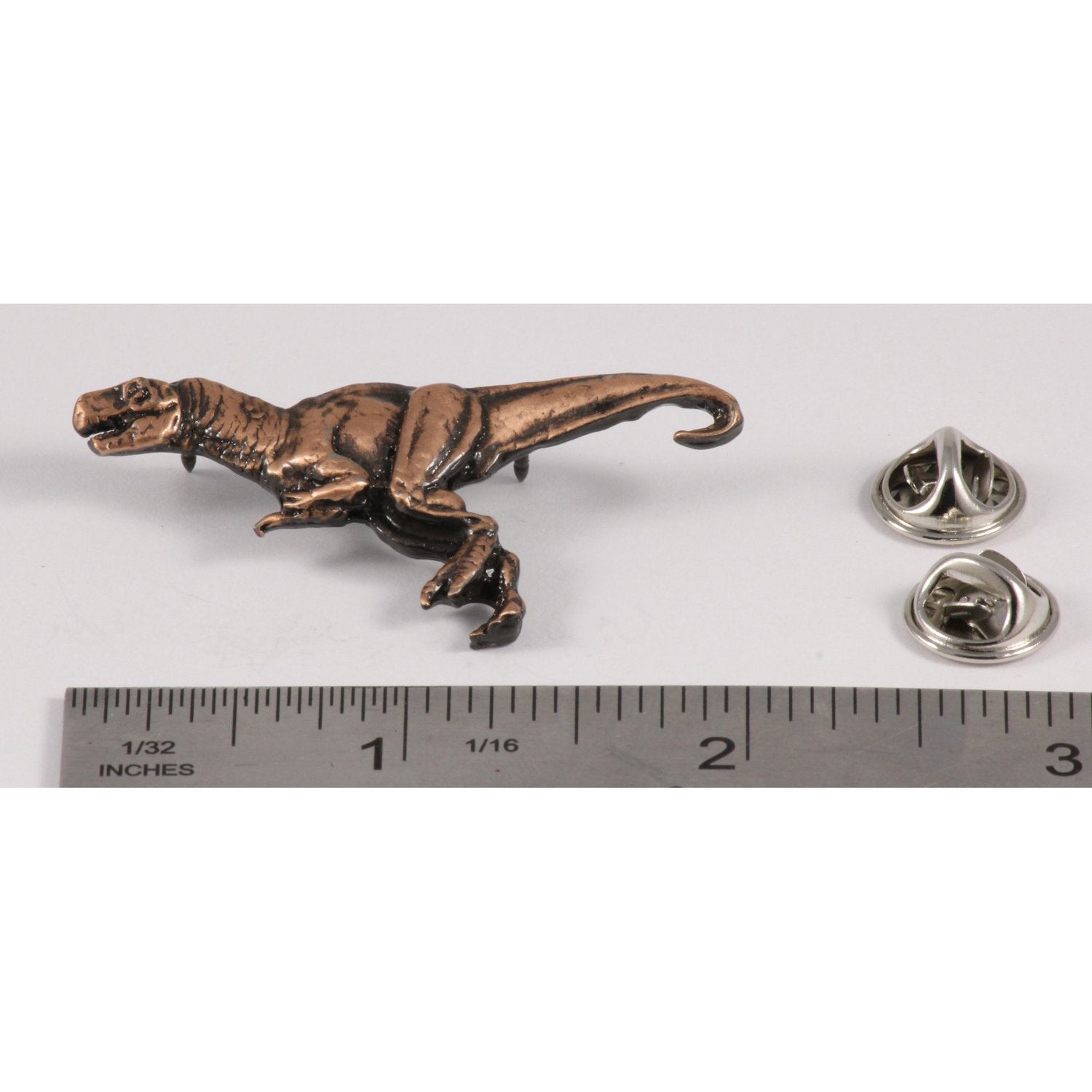 A handcrafted Tyrannosaurus Rex Pin next to a ruler, available for sale at Creativeartisan.com - the image offers a sense of scale