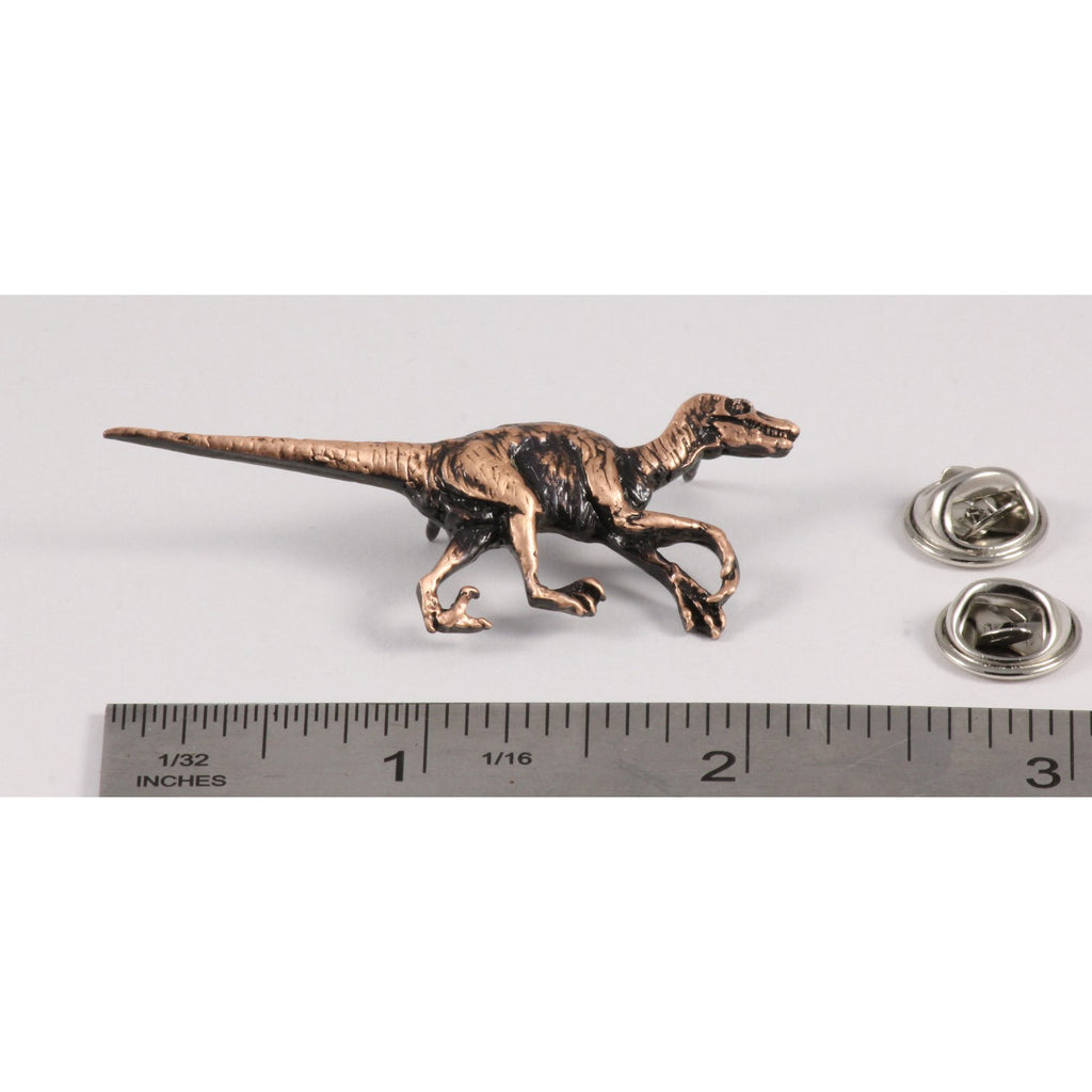 A handcrafted Velociraptor Pin next to a ruler, available for sale at Creativeartisan.com - the image offers a sense of scale