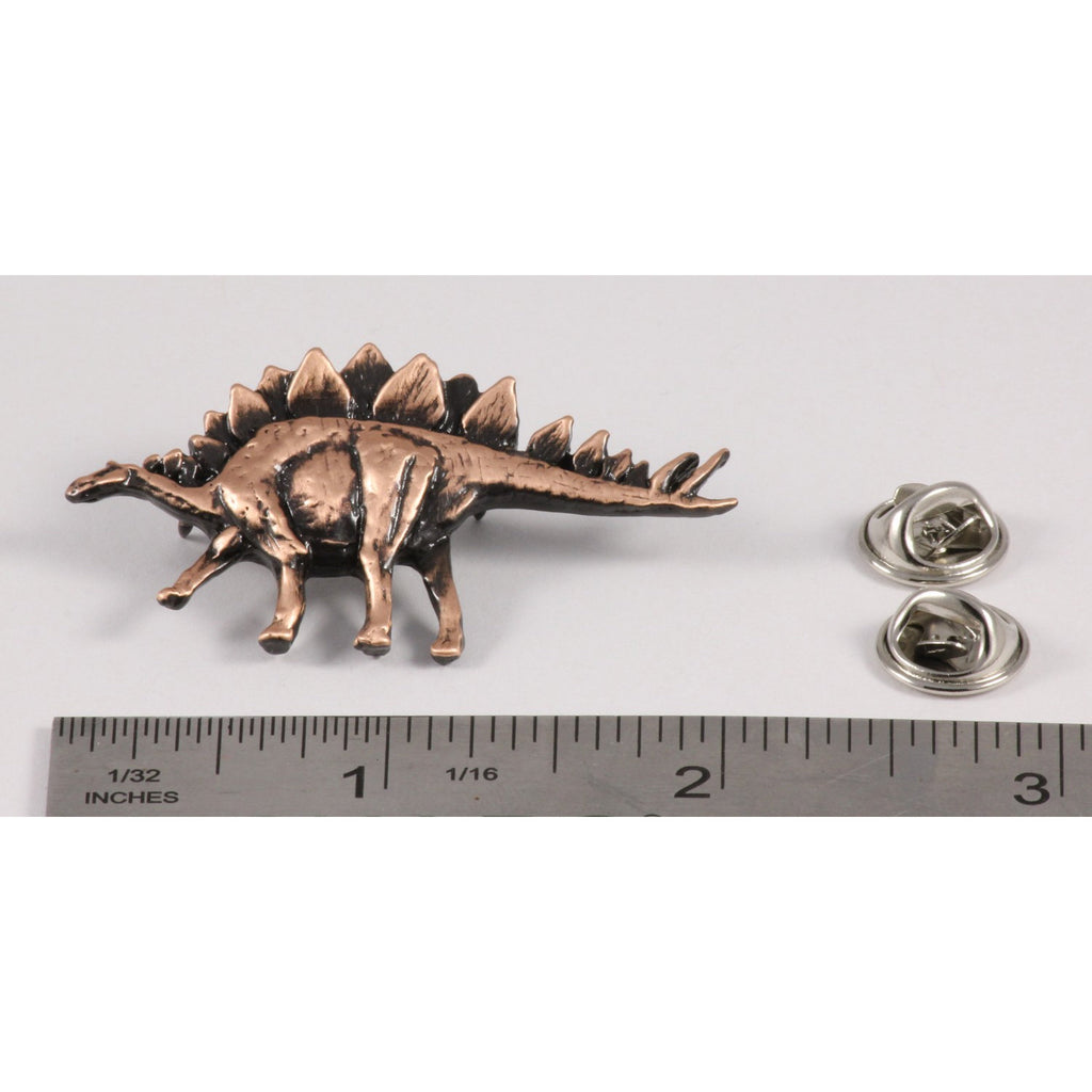 A handcrafted Stegosaurus Pin next to a ruler, available for sale at Creativeartisan.com - the image offers a sense of scale