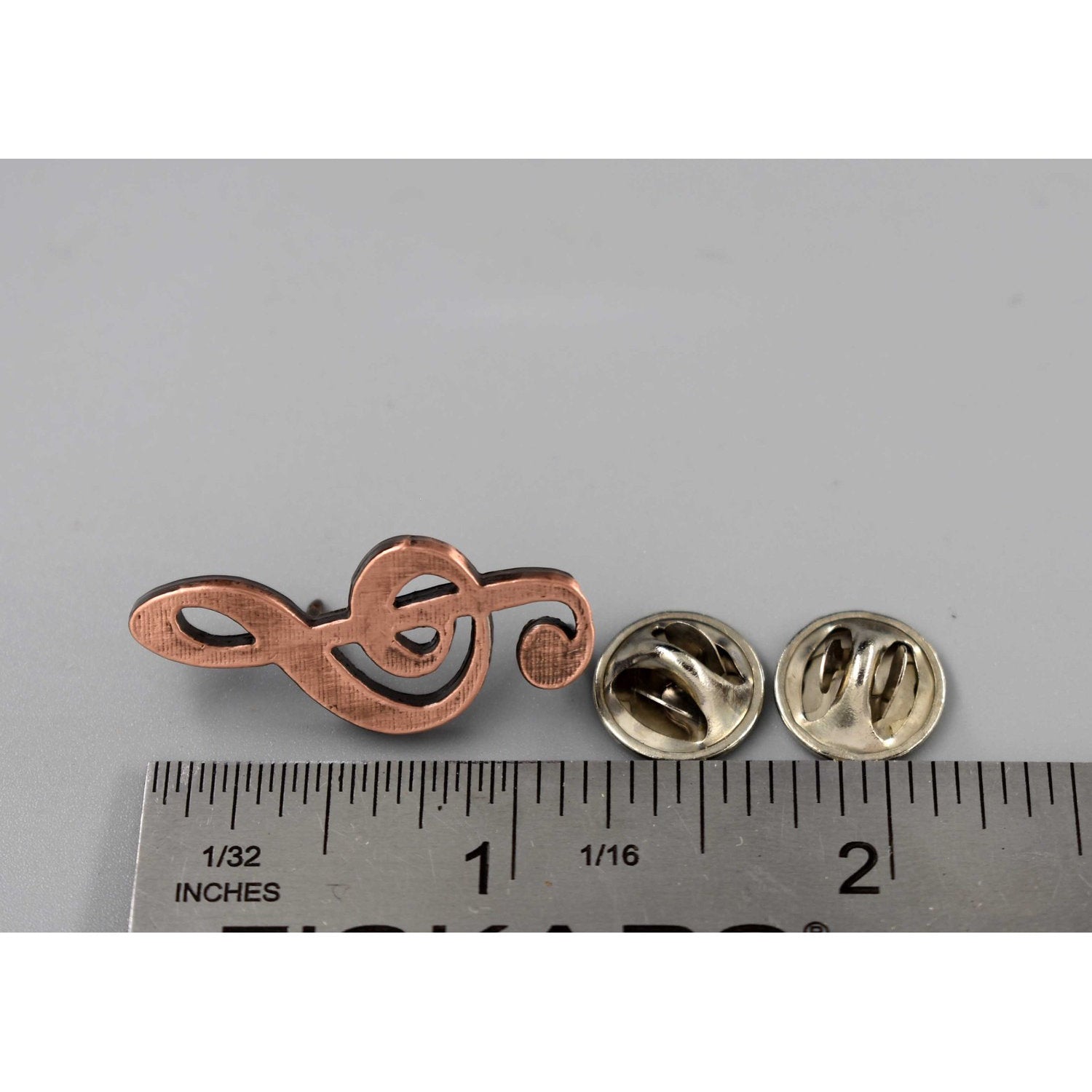 A handcrafted Treble Clef Musical Note Pin next to a ruler, available for sale at Creativeartisan.com - the image offers a sense of scale