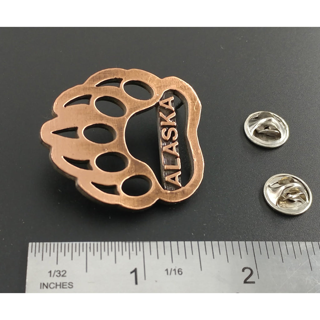 A handcrafted Bear Print Alaska Pin next to a ruler, available for sale at Creativeartisan.com - the image offers a sense of scale