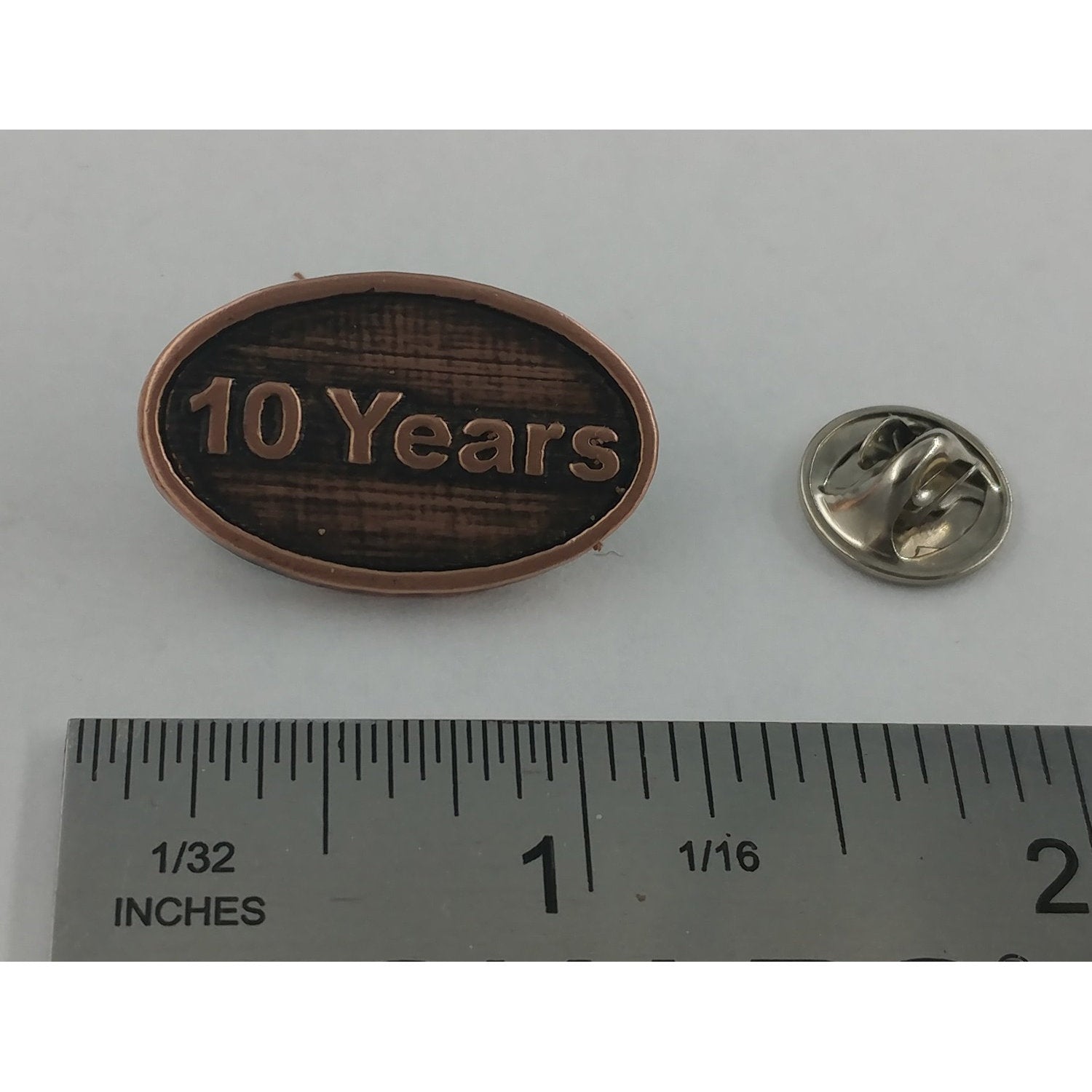 A handcrafted 10 Year Pin next to a ruler, available for sale at Creativeartisan.com - the image offers a sense of scale