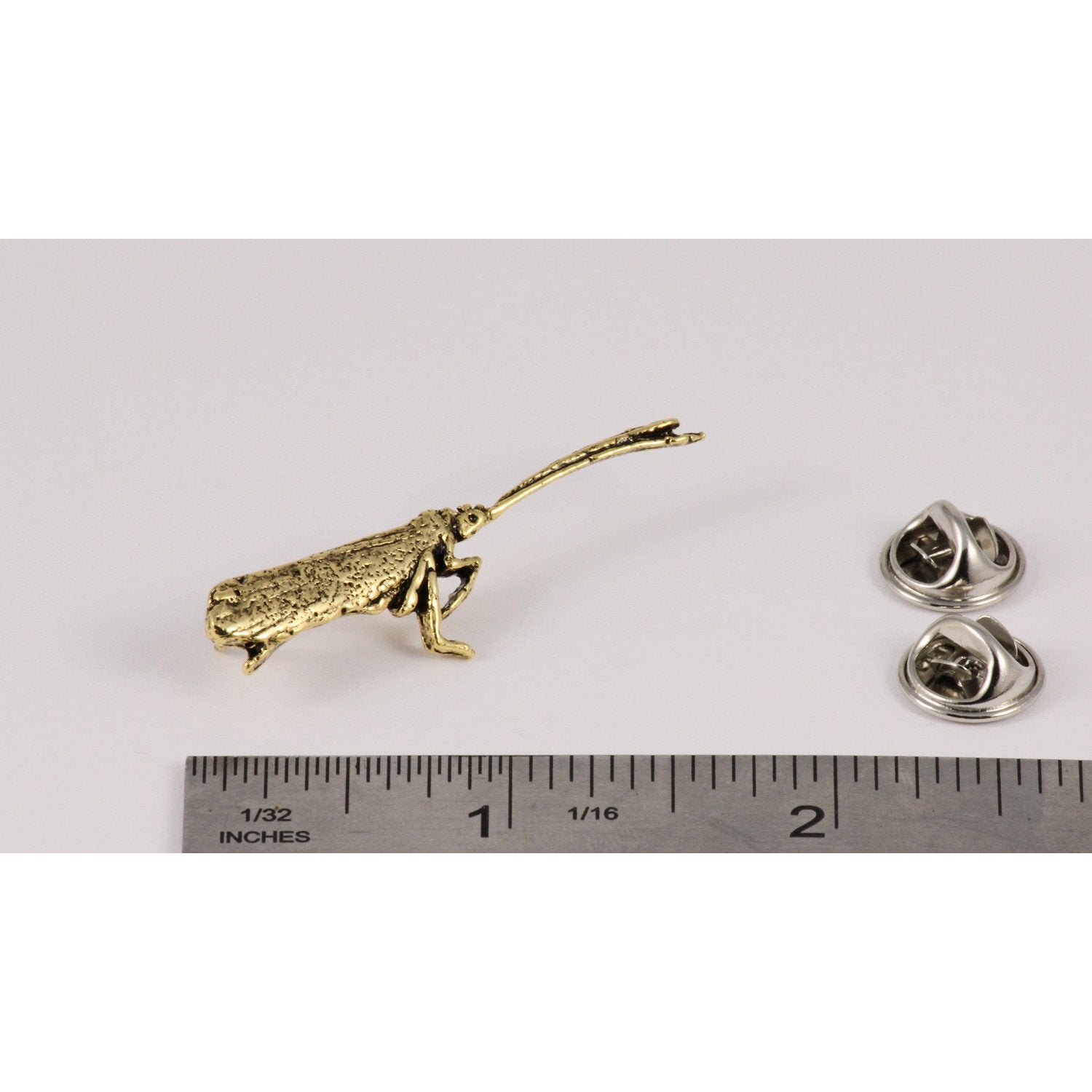 A handcrafted Caddis Pin next to a ruler, available for sale at Creativeartisan.com - the image offers a sense of scale