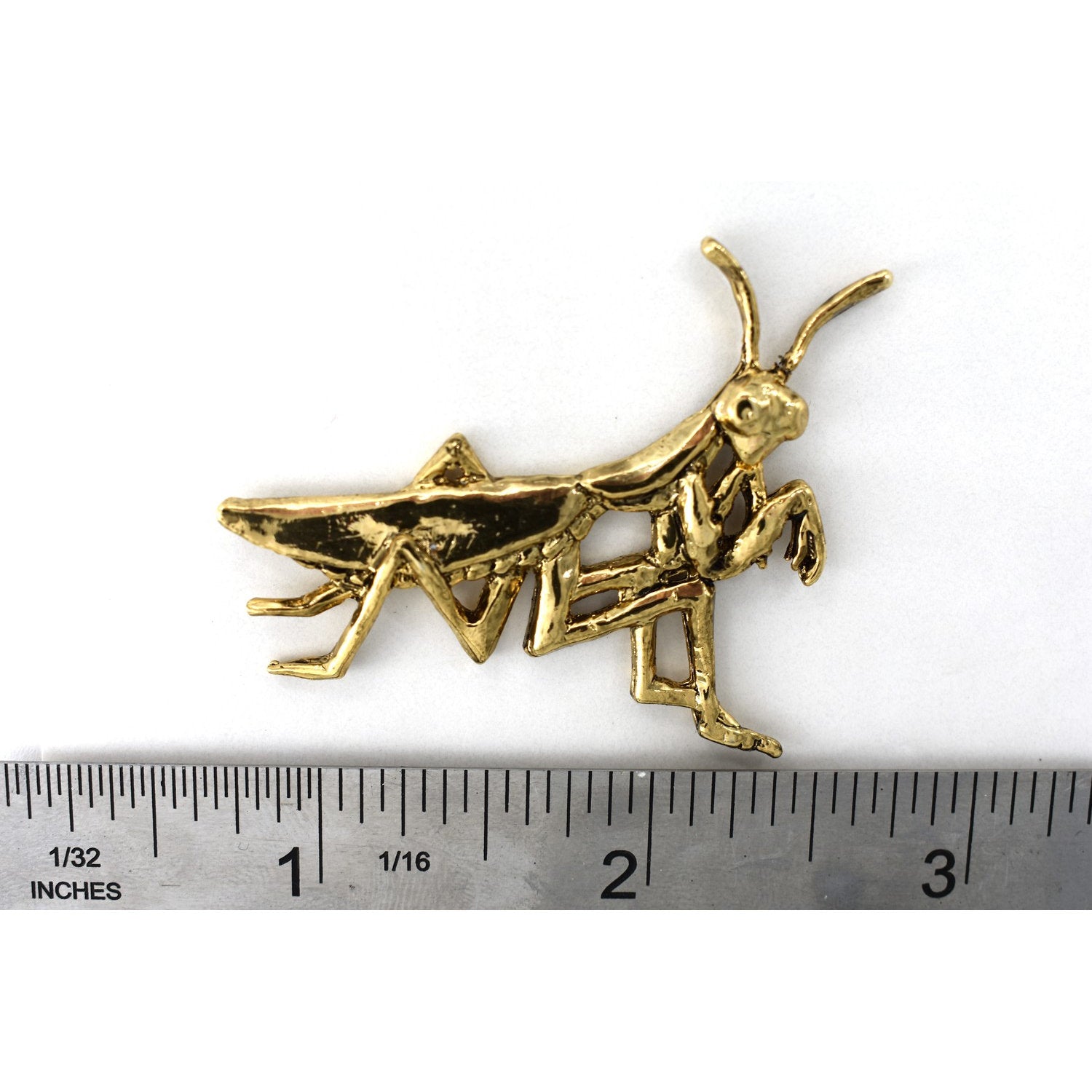 A handcrafted Praying Mantis Pin next to a ruler, available for sale at Creativeartisan.com - the image offers a sense of scale