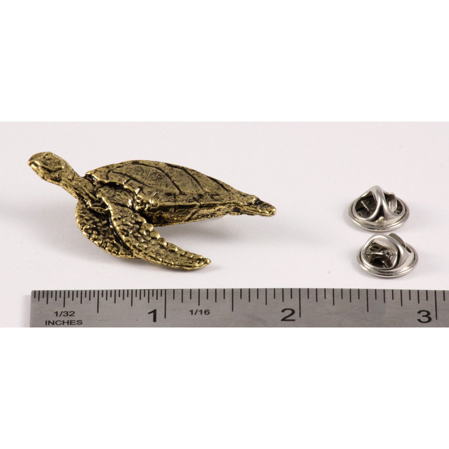 A handcrafted Sea Turtle Side View Pin next to a ruler, available for sale at Creativeartisan.com - the image offers a sense of scale