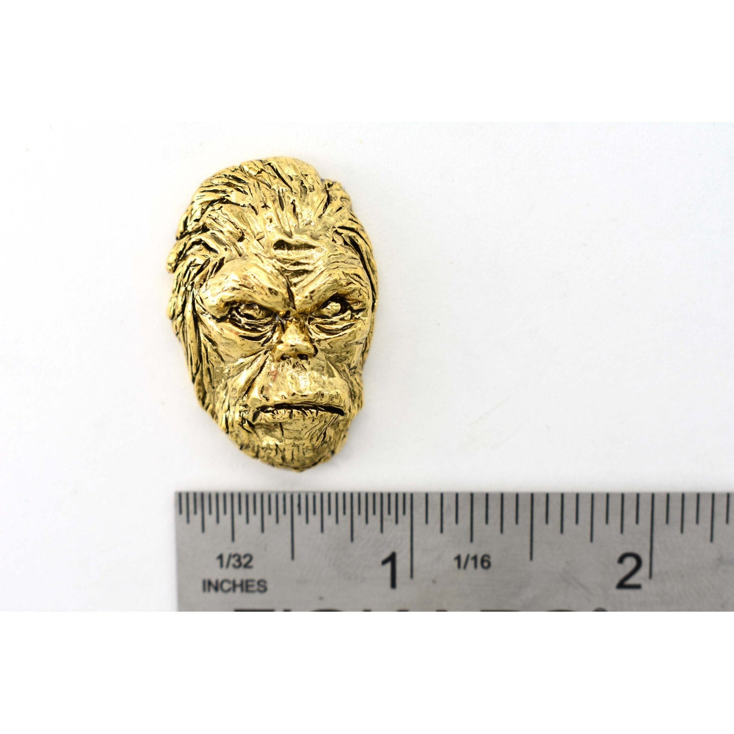A handcrafted Sasquatch Bigfoot Head Pin next to a ruler, available for sale at Creativeartisan.com - the image offers a sense of scale