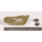 A handcrafted Sasquatch Bigfoot Footprint Pin next to a ruler, available for sale at Creativeartisan.com - the image offers a sense of scale