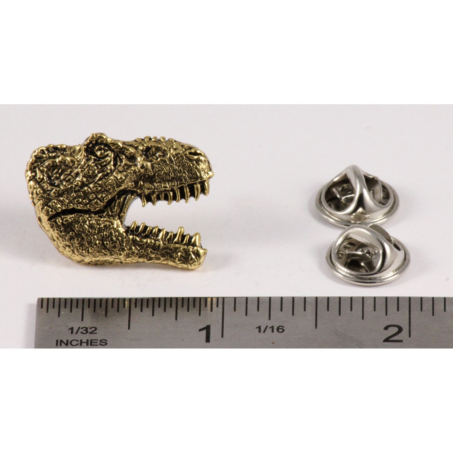 A handcrafted Tyrannosaurus Rex Head Pin next to a ruler, available for sale at Creativeartisan.com - the image offers a sense of scale