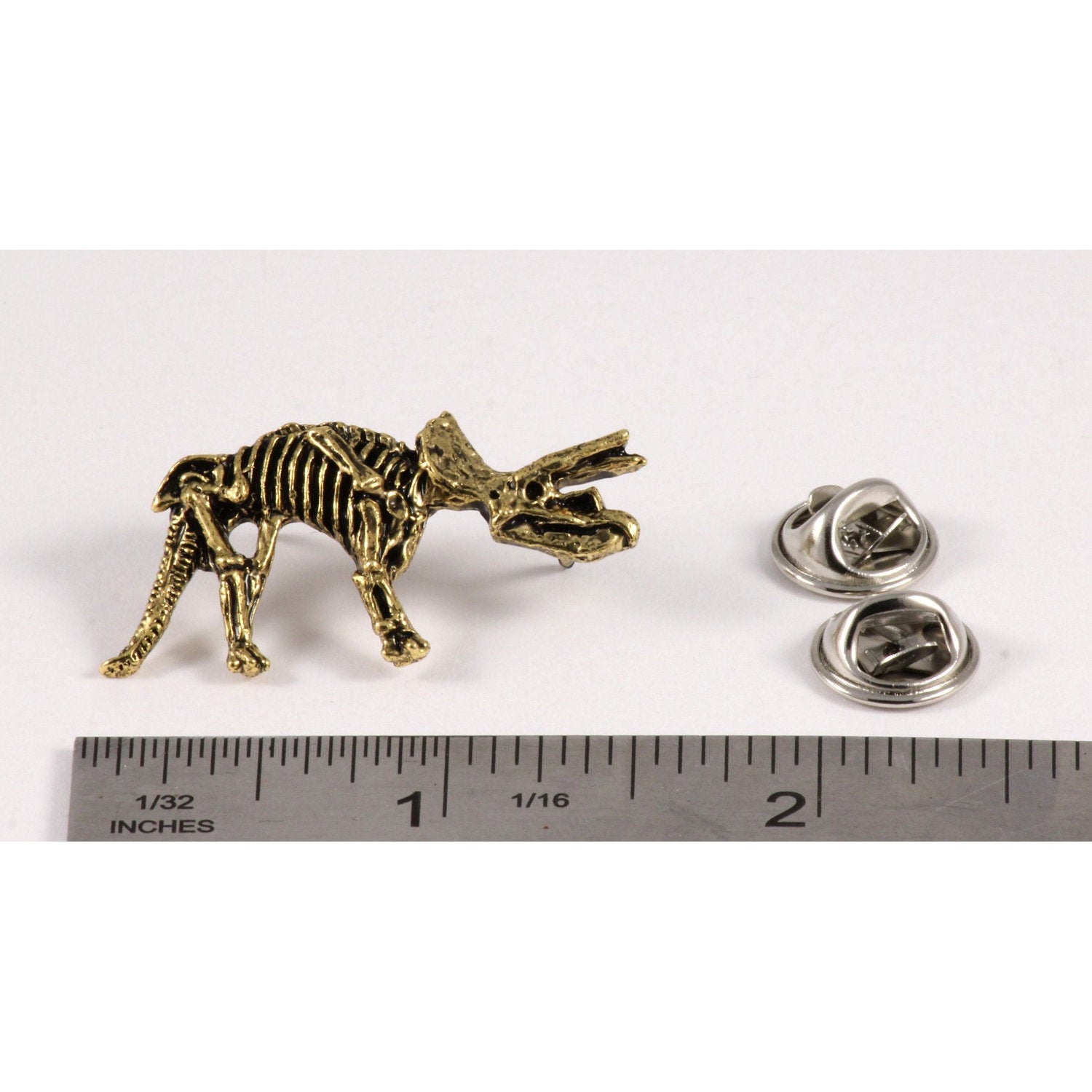 A handcrafted Triceratops Fossilized Full Body Pin next to a ruler, available for sale at Creativeartisan.com - the image offers a sense of scale