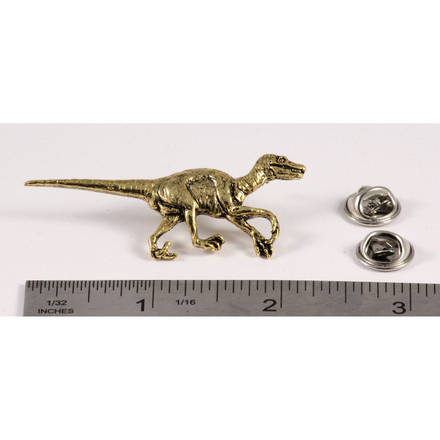 A handcrafted Velociraptor Pin next to a ruler, available for sale at Creativeartisan.com - the image offers a sense of scale