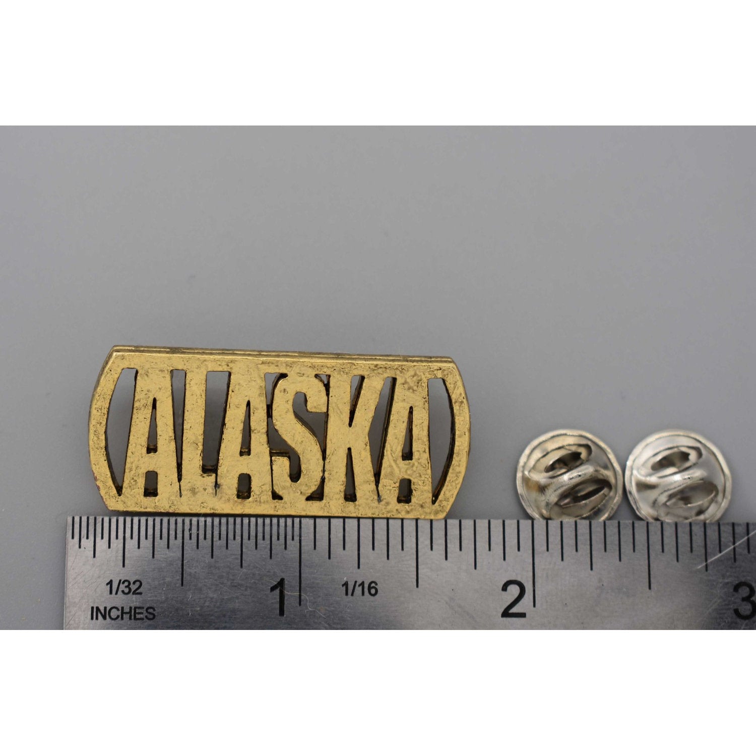 A handcrafted Alaska Cutout Pin next to a ruler, available for sale at Creativeartisan.com - the image offers a sense of scale